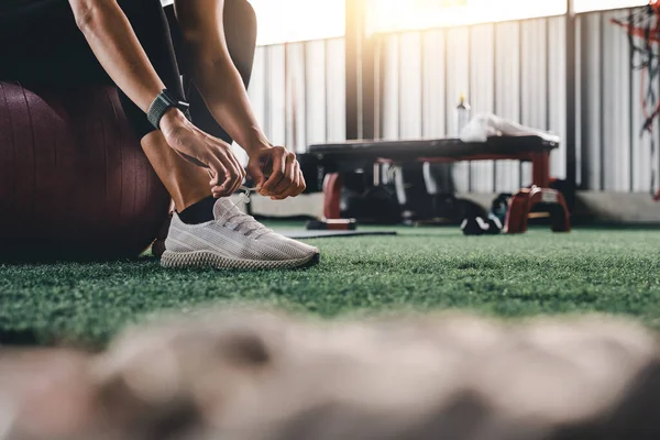 Женщина сидит на спортзале мяч завязывая шнурки и готовится к фитнесу — стоковое фото