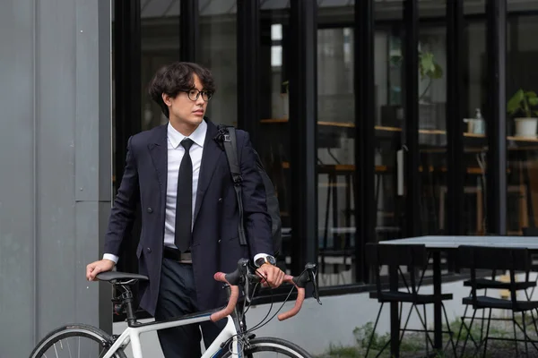 Azjatycki biznesmen pchający rano rower przygotowujący się do jazdy do pracy. Transport ekologiczny — Zdjęcie stockowe
