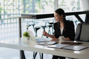 Ofiste dizüstü bilgisayarla çalışan Asyalı çekici bir iş kadını. Yan görünüm