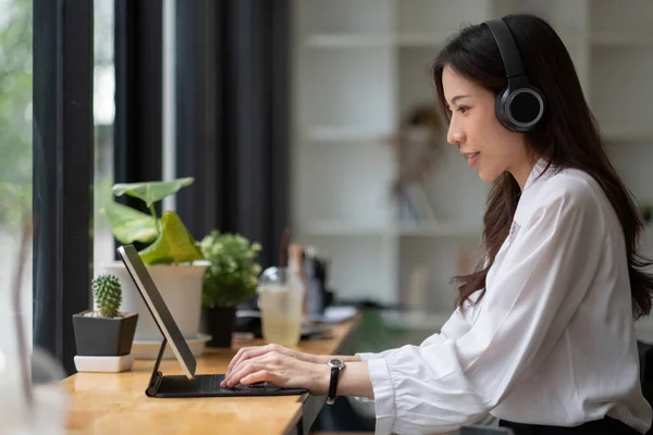 Zijaanzicht hoofd schot glimlachende Aziatische vrouw freelancer dragen headset, communiceren met de klant via video computer oproep. Millennial aangename professionele vrouwelijke leraar geven online taalcursus — Stockfoto