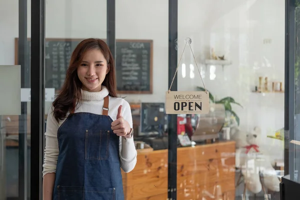 Retrato de um empresário asiático sorridente em pé atrás de seu balcão de café com placa de sinal aberto — Fotografia de Stock