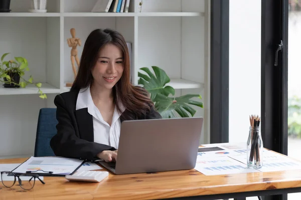 Ofisinde dizüstü bilgisayarla çalışan Asyalı çekici bir iş kadınının fotoğrafı. — Stok fotoğraf