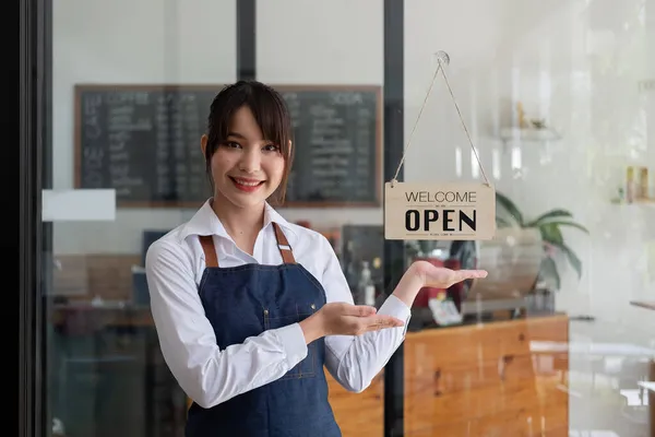 Retrato de um empresário asiático sorridente em pé atrás de seu balcão de café com placa de sinal aberto — Fotografia de Stock