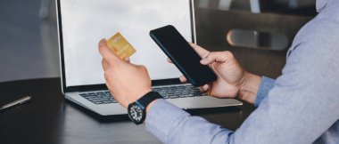 Çevrimiçi ödeme, akıllı telefonu tutan adamların ellerini kapat ve online alışveriş için kredi kartını kullan.