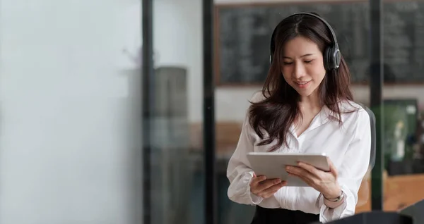 Vrolijke aziatische vrouw dragen draadloze headset glimlachen met digitale tablet — Stockfoto