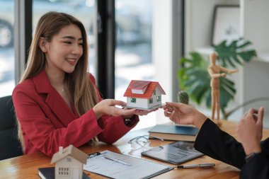 Real estate agent sales manager holding house model to customer after signing rental lease contract of sale purchase agreement, concerning mortgage loan offer for and house insurance