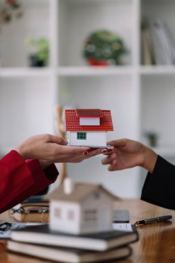 Real estate agent sales manager holding house model to customer after signing rental lease contract of sale purchase agreement, concerning mortgage loan offer for and house insurance