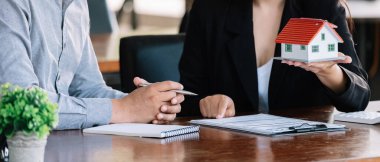 Real estate agent sales manager holding house model to customer after signing rental lease contract of sale purchase agreement, concerning mortgage loan offer for and house insurance