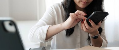 Close up image of an asian woman holding , using and looking at mobile phone.