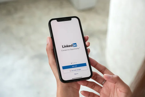 ChiANG MAI, THAILAND, JAN 15, 2022: A women holds Apple iPhone 13 Pro max with LinkedIn application on the screen. LinkedIn 은 스마트폰을 위한 사진 공유 앱이다. — 스톡 사진
