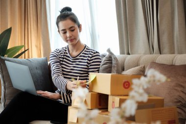 Başlangıçta küçük işletme KOBİ 'si, dizüstü bilgisayar kullanan girişimci sahibi ve paket ürün kutusu hazırlamak için çevrimiçi alışveriş siparişini kontrol ediyor. Çevrimiçi fikirler satılıyor.