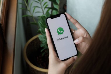 CHIANG MAI, THAILAND - 15 Ocak 2022: Ekranda sosyal ağ servisi WhatsApp ile iPhone 12 'yi tutan kadın. iPhone Apple tarafından oluşturuldu ve geliştirildi.