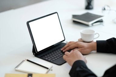Ofisteki reklam mesajınız için bilgisayarında boş bir kopya ekranı ile çalışan genç bir adam ofis masasındaki dizüstü bilgisayarını kullanarak iş adamlarının ellerini arka planda tutuyor.