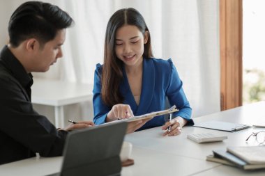 İki meslektaş masadaki belgelerle verileri tartışıyor. Pazardaki durumu tartışmak için iş adamlarını toplayın..