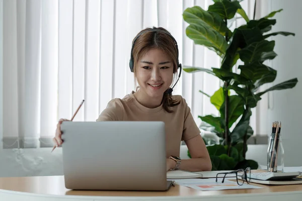 헤드폰을 끼고 컴퓨터를 사용하여 현대 사무실에서 일하는 아름다운 젊은 사업가가 웃는 모습, 사업가들은 온라인 마케팅 프리랜서인 전자 상거래 텔레마케팅 컨셉 — 스톡 사진