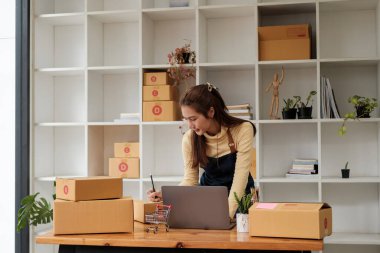 Küçük işletme girişimcisi KME ya da kutulu laptop kullanan serbest çalışan Asyalı kadın, elini kaldıran genç başarılı Asyalı kadın, çevrimiçi pazarlama kutusu ve teslimatı, KME kavramı