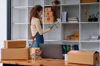 Genç Asyalı kadın eve nakliye siparişini kontrol ediyor, iş sahibi kadın internet üzerinden iş kuruyor, KOBİ, Teslimat projesi, Çevrimiçi iş veya KOBİ konsepti olan kadın.