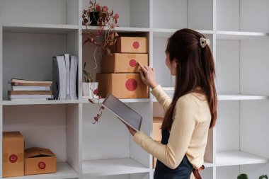 Genç Asyalı kadın eve nakliye siparişini kontrol ediyor, iş sahibi kadın internet üzerinden iş kuruyor, KOBİ, Teslimat projesi, Çevrimiçi iş veya KOBİ konsepti olan kadın.