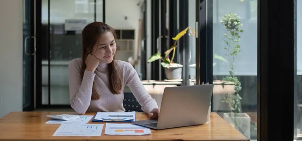 Χαμογελαστή νεαρή Ασιάτισσα επιχειρηματίας που χρησιμοποιεί υπολογιστή στο χώρο εργασίας του γραφείου στο σπίτι, ευτυχισμένη Κορεάτισσα υπάλληλος που εργάζεται σε φορητό υπολογιστή, ελκυστική γυναίκα φοιτήτρια που σπουδάζει επικοινωνώντας online με φορητό υπολογιστή. — Φωτογραφία Αρχείου