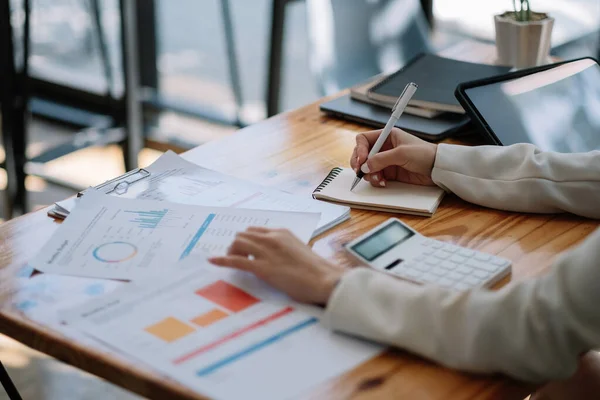 Affärskvinna hand med diagram och anteckna på anteckningsblocket. Rapporteringsunderlag och affärsplanering med affärsplan. — Stockfoto