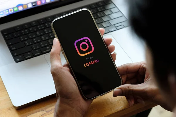 CHIANG MAI, TAILANDIA - FEB 26 2022: Un hombre tiene Apple iPhone 13 con Instagram aplicación en la pantalla en la cafetería. Instagram de meta es una aplicación para compartir fotos para teléfonos inteligentes. — Foto de Stock