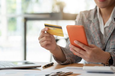 Kadın internet üzerinden akıllı telefondan alışveriş yapıyor, kredi kartı kullanıyor, kadın internet bankacılık sistemine cep telefonundan giriyor, cihaz üzerinden ödeme yapıyor, internet üzerinden faturaları ödüyor, ekran modeli yapıyor..