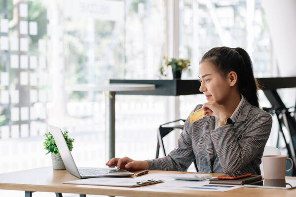 Happy asian woman hands holding credit card and using laptop computer. Online shopping concept.