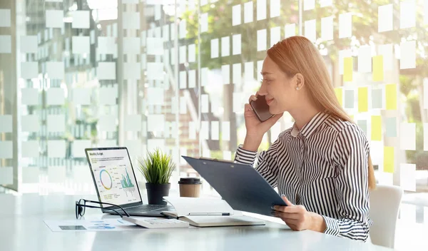 Glimlachende Aziatische zakenvrouw analist grafiek financieel verslag en bel bankier voor advies - Financial Concept — Stockfoto