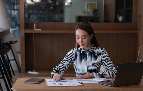 Attractive asian woman using laptop while doing homework making video call abroad using internet friend connection, business women use computer analysis finance data