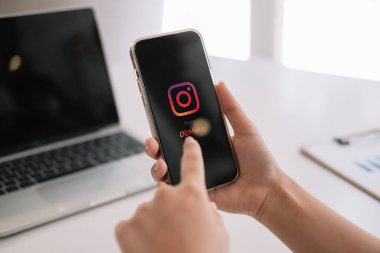 CHIANG MAI, THAILAND - MAR 06 2022: Kafedeki ekranda Apple iPhone 13 uygulaması olan bir kadın var. Instagram akıllı telefonlar için fotoğraf paylaşım uygulamasıdır