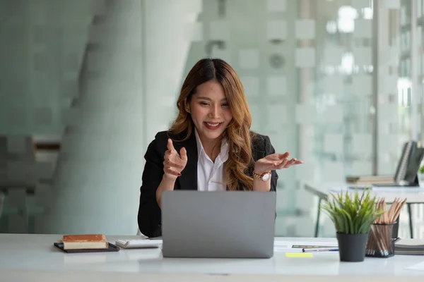 Porträt einer lächelnden asiatischen Frau, die per Videoanruf Hallo sagt. Erfolgreiche junge Frau im weißen Anzug. Businesskonferenz per Laptop — Stockfoto