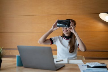 VR gözlüklü genç Asyalı kadın evde finans sektöründe çalışıyor.