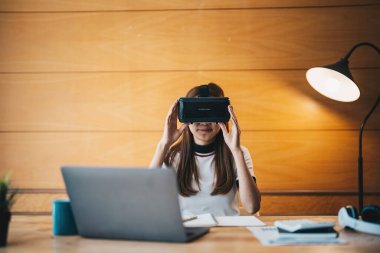 VR gözlüklü genç Asyalı kadın evde finans sektöründe çalışıyor.