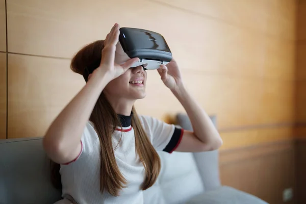 Excite asian woman playing online game with vr glasses and controller at her home