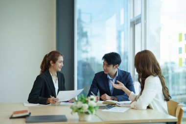 Bir grup Asyalı iş toplantısı ve yeni bir başlangıç projesi üzerinde tartışıyorlar. Yaratıcı iş adamları strateji analizi ve belge raporlarıyla beyin fırtınası yapmayı planlıyorlar..