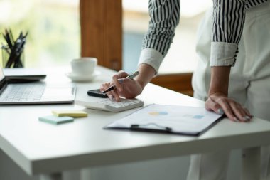 Hesap makinesi ve dizüstü bilgisayarı kullanarak ahşap masa, vergi, muhasebe, istatistik ve analitik araştırma konseptine matematik finansmanı sağlayan İş kadını kapat