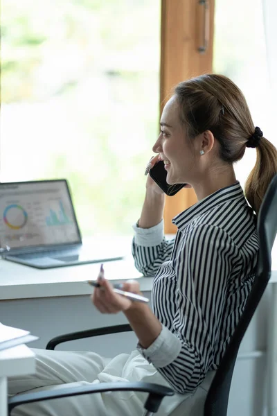 Πορτρέτο Γυναίκα Επιχειρηματίας. Χαρούμενη Ασιάτισσα επιχειρηματίας μιλώντας στο τηλέφωνο εργασίας σε φορητό υπολογιστή στο σύγχρονο γραφείο. — Φωτογραφία Αρχείου
