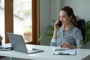 Genç muhasebeci elinde akıllı telefonla pazarlama danışmanlarını arıyor ve küresel iş piyasasındaki satış artışını analiz etmek için dizüstü bilgisayar kullanıyor. muhasebe kavramı