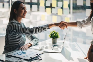 Genç Asyalı iş adamları ofiste el sıkışıyor. Başarılı toplantı bitiriliyor.