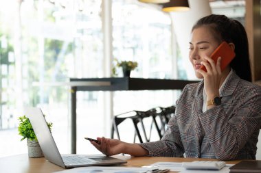 Genç muhasebeci elinde akıllı telefonla pazarlama danışmanlarını arıyor ve küresel iş piyasasındaki satış artışını analiz etmek için dizüstü bilgisayar kullanıyor. muhasebe kavramı