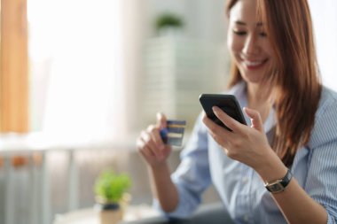 Genç ve güzel Asyalı bir kadın akıllı telefon ve kredi kartını fotokopi alanı olan online alışveriş için kullanıyor. E-ödeme teknolojisi, alışveriş kolik yaşam tarzı veya cep telefonu finansal uygulama kavramı