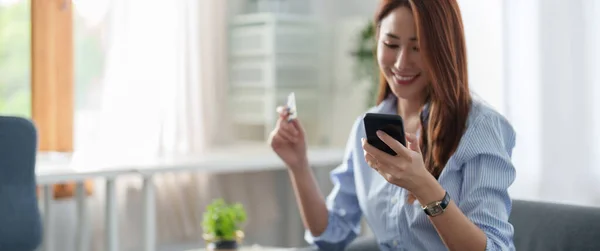 コピースペース付きの自宅でオンラインショッピングのためのスマートフォンやクレジットカードを使用して若い美しいアジアの女性。電子決済技術、ショッピングライフスタイル、携帯電話金融アプリケーションの概念 — ストック写真