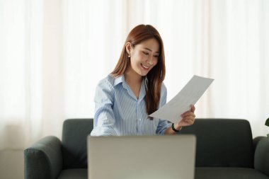 Çekici Asyalı kadın evde bilgisayar ve evrak işleriyle finans için çalışıyor..