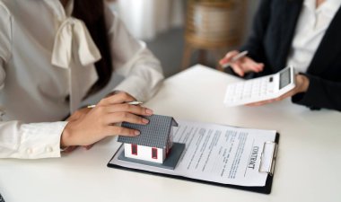 Emlakçı veya banka memuru, konut satın alma sözleşmesi veya ofis kredileri ve faiz oranları olan müşteriye kredi faizini açıklar.