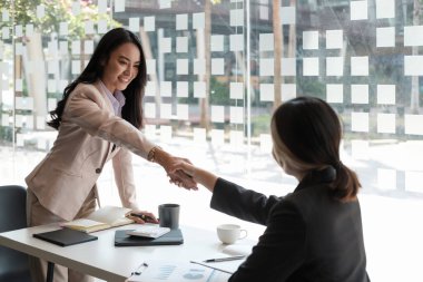 Genç Asyalı iş adamları ofiste el sıkışıyor. Başarılı toplantı bitiriliyor.