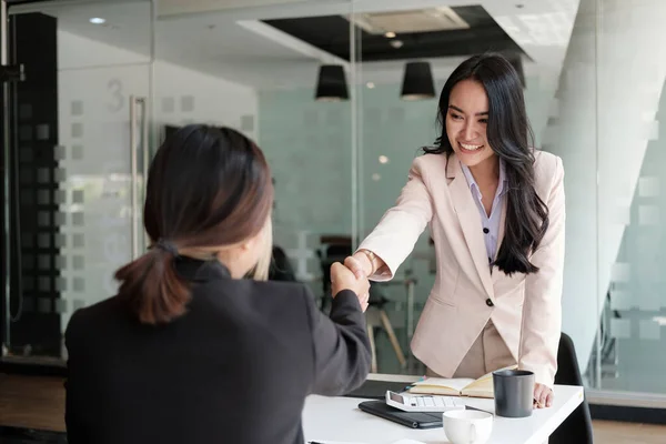 Mladí asijští obchodníci si v kanceláři potřásají rukama. Dokončení úspěšné schůzky. — Stock fotografie