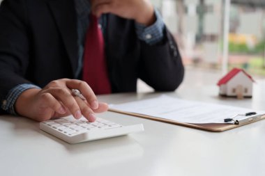 Mali işler yapan ve gayrimenkul yatırımının maliyetini hesaplayan bir işadamı.