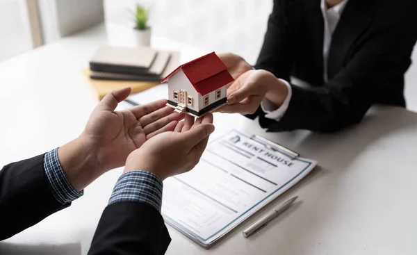 Immobilienmakler mit Hausmodell spricht mit Kunden über den Kauf einer Hausratversicherung. Eigenheimversicherungskonzept — Stockfoto