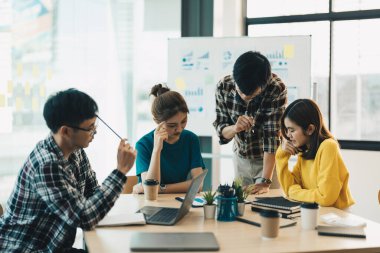 Bir grup Asyalı genç iş adamı iş görüşlerini tartışmak için bir araya geliyor. İş arkadaşları toplantı odasında fikir alışverişinde bulunuyor, işbirliği konsepti.