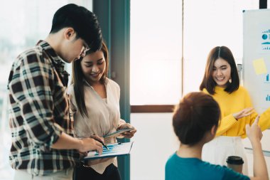 Takım çalışması, beyin fırtınası konsepti. Genç Asyalı yaratıcı yöneticiler modern ofiste yeni bir başlangıç projesi üzerinde çalışıyorlar.